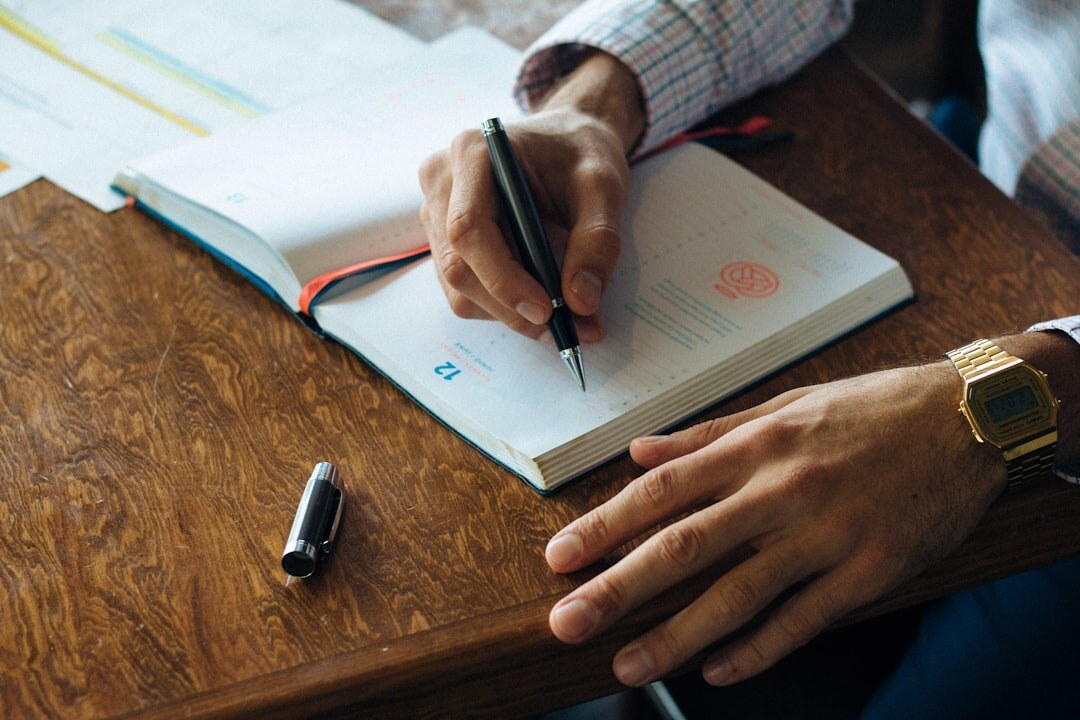Close-up of hands writing in a personal journal with a pen